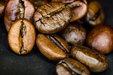 Brown roasted coffee beans on black background, close up, macro