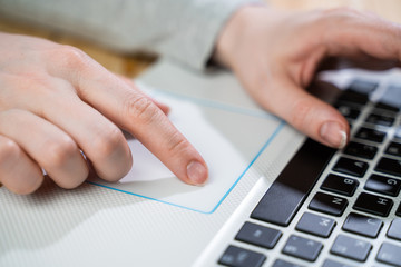 Closeup image of hands using and typing on laptop keyboard on the table on wooden table