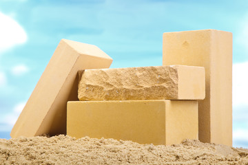 Four yellow ceramic bricks on the sand at the blue sky background