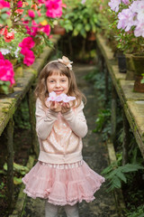 Little girl playing with flowers in greenhouse.