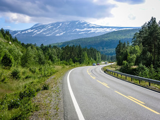 Fototapeta premium The asphalted mountain road in Norway passes through the forest.