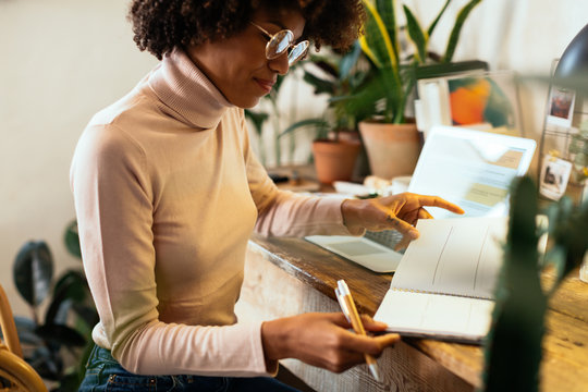 Afro businesswoman working in office full of plants.