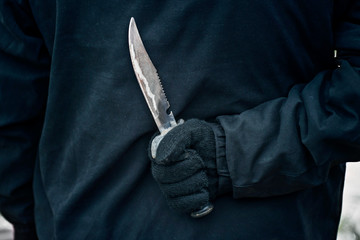 Man with the knife. Hand with a knife behind his back. Criminal with knife weapon hidden behind his...
