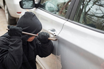 Car thief trying to break into a car with a screwdriver. Thief trying to pick the lock of a parked car