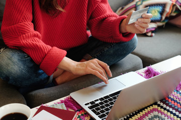 Young woman making online shopping with her laptop sitting on the sofa in the living room