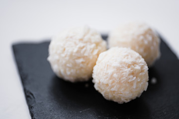 White coconut candy balls in plate shale dishes on rustic wooden background.