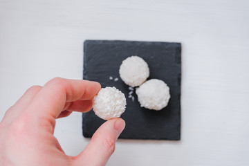 Fototapeta na wymiar White coconut candy balls in plate shale dishes on rustic wooden background with a cup of tea.