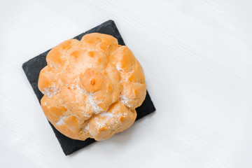 Sweet bun with cream on a shale dishes and wooden background.