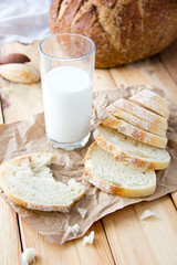 a glass of milk and cut bread on a wooden table and scattered crumbs
