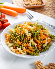Multicolored pasta with vegetable on wooden background ve vegetables
