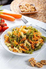 Multicolored pasta with vegetable on wooden background ve vegetables