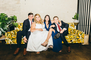 Bride and Her Siblings Sit on Couch for Portrait