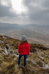 une jeune femme de dos en tenue de trekking au sommet d'une montagne 