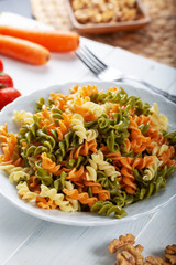 Multicolored pasta with vegetable on wooden background ve vegetables