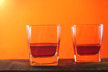 Glasses with a drink on a wooden board. red yellow background.