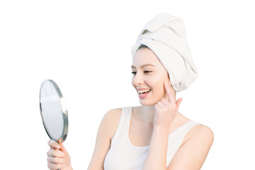 portrait of attractive caucasian smiling woman on white studio shot cleaning her face looking at the mirror applying Foundation On Facial Skin. Isolated on a white background © sofiko14
