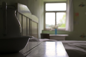 Fototapeta premium Interior of vintage living room. In the scene a bed, a bedside table, a basin and a water jug.