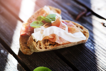 Small sandwiches with meat and basil on the black table.