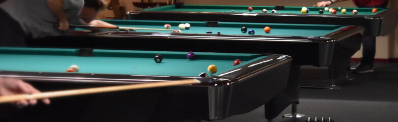 many people around pool table playing pool in a club and one player getting ready for his shot