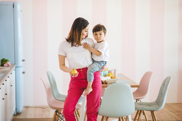 Young mother with her cute little son standing in cozy kitchen