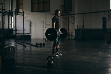 Muscular man lifting a barbell in gym