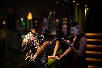 Woman checking her smart phone on a rooftop bar