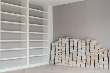 Stacks of books waiting to be put on the empty shelves