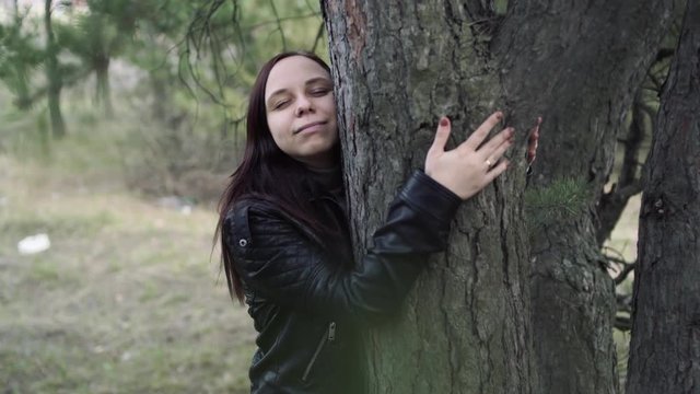 Young woman hugging tree in the forest. Smiling young woman nature lover relax on summer day hug a tree enjoy in beautiful day