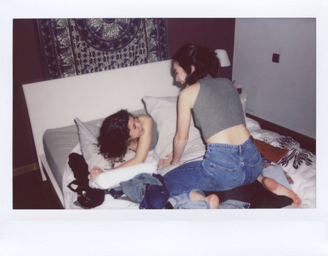Girls playing pillow fight on bed.