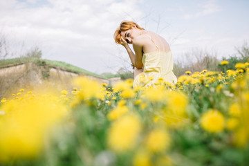 Young woman in dandelion field in early spring
