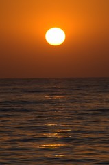 Fototapeta na wymiar Sunset with large yellow sun under the sea surface