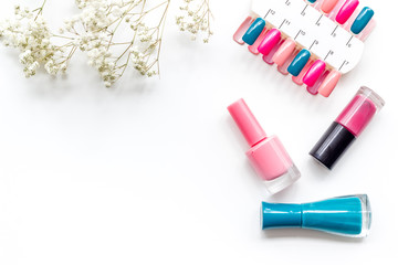 flowers, palette and nail polish for nail artist work on white desk background top view mock up