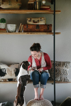 woman sitting on shelf bench gives attention to her dog