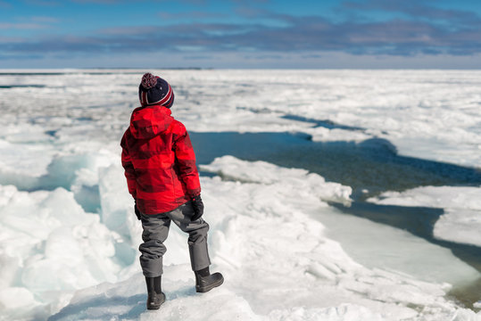 Boy thoughtfully gazes across frozen lake on warming fragile pla