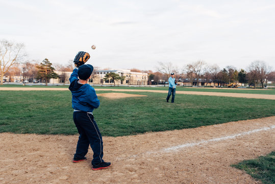 Son catching a baseball from his Dad on a field