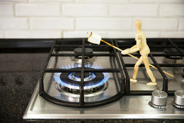 Cook marshmallows on fire. Wooden mannequin. Wooden mannequin preparing marshmallows on fire. Wooden man.