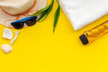 Planning vacation to the seaside with straw hat, sun glasses, sunscreen lotion on yellow background top view mock-up