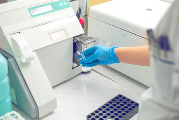 Woman working in a laboratory on a modern machine for blood testing. Doctor checks the blood of the patients. Blood research in a modern scientific workplace