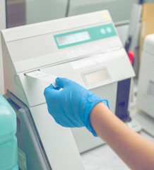 Woman working in a laboratory on a modern machine for blood testing. Doctor checks the blood of the patients. Blood research in a modern scientific workplace