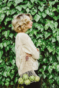 Blonde womam with apples in a net bag