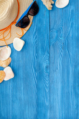 Summer travaling to the sea with straw hat, sun glasses, shells on blue background top view mock up