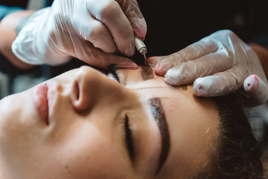 A young woman having her eyebrows micro bladed