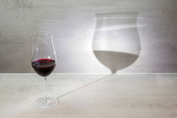 One glass of red wine casts shadow on gray background
