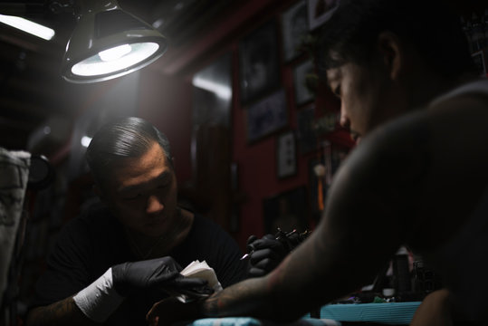 Professional asian tattooer makes a tattoo.