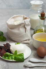 Ingredients for making cake - flour, eggs, milk or buttermilk, olive oil, salt, mozzarella, basil, dried tomatoes. Food background. Copy space.