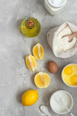 Ingredients for making cake - flour, eggs, milk or buttermilk, olive oil, sugar, lemon, baking powder. Food background. Bake sweet cake dessert concept. Copy space.