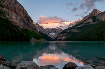 Lake Louise reflection with rocks, snow and pink clouds