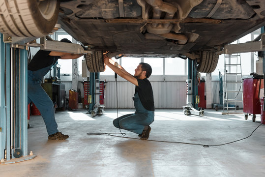 Repairmen working with car together