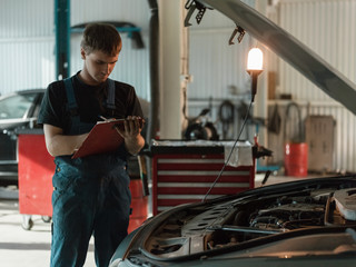 Repairman writing on clipboard in garage