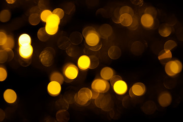 Abstract gold bokeh on black background. Defocused yellow lights, abstract texture